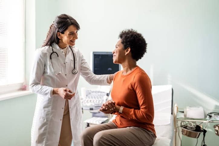 A woman speaking with her doctor and getting a health check up. 