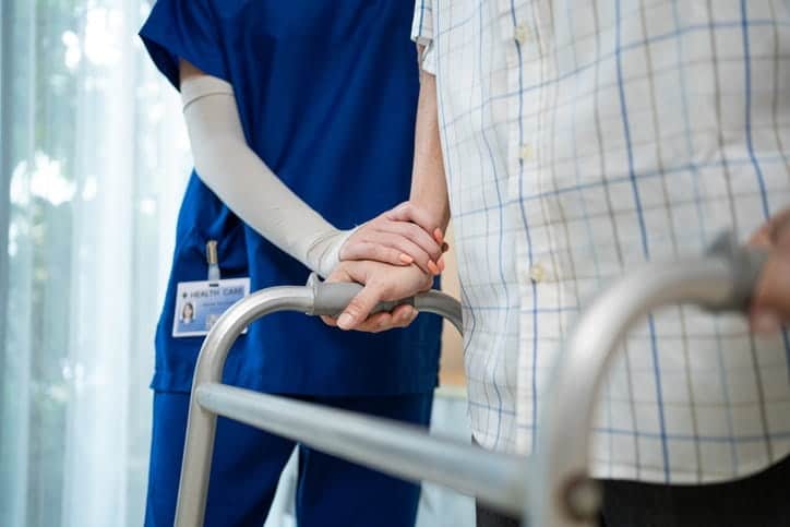 A nurse assisting a patient with a walker at a skilled nursing facility. 