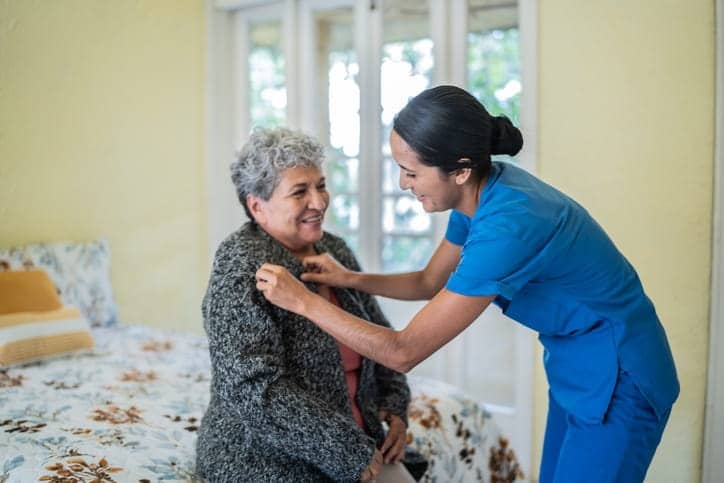 A nurse is assisting a patient get dressed in a skilled nursing facility. 