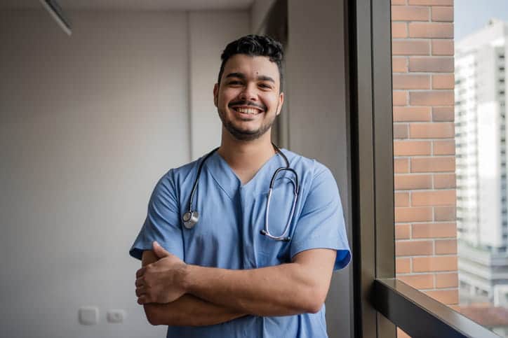 A nurse smiling for the camera with his arms crossed.