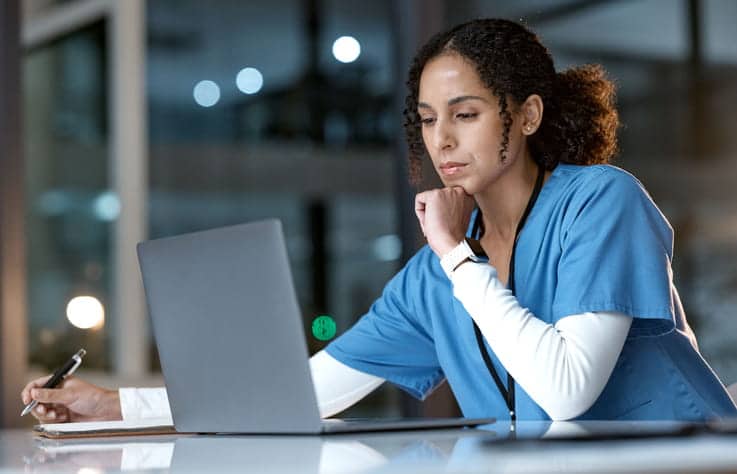 A SNF nurse is studying on her laptop. 