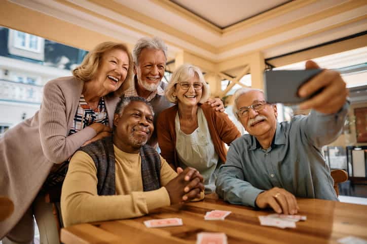 A group of five seniors take a selfie together at a skilled nursing facility. 