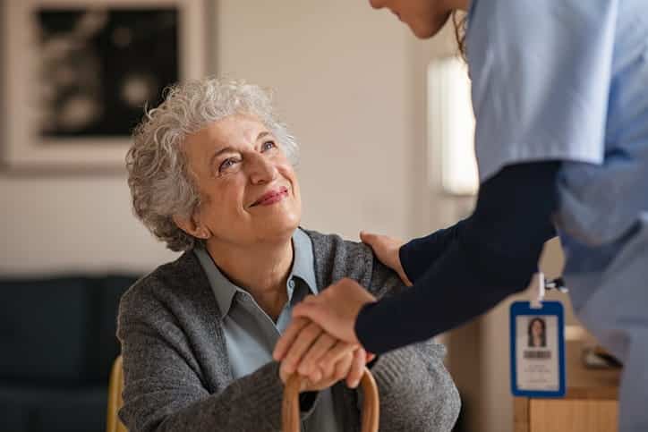 An elderly woman smiling at the nurse assisting her. 