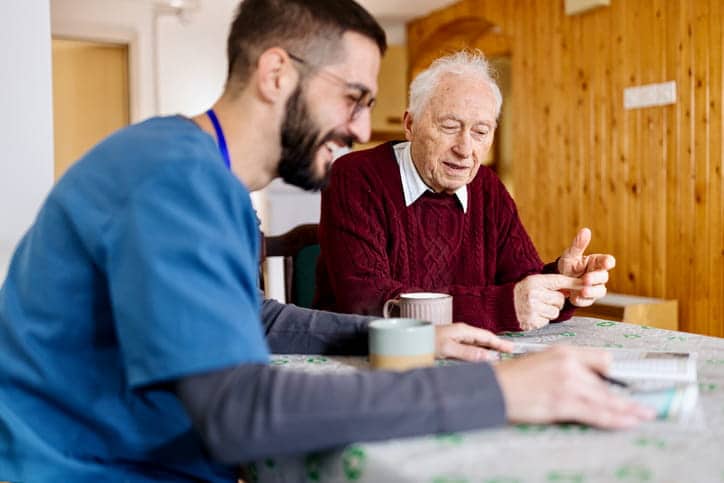 A caretaker is laughing with an elderly patient in assisted living. 