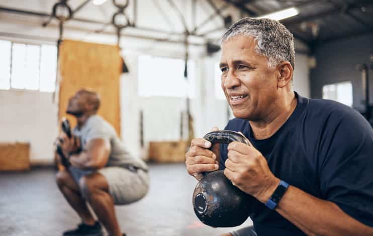 An elderly man working out with an instructor. 