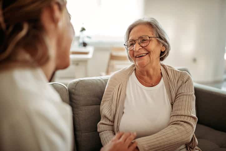 A Health Aid Talking To Their Patient Inside A Skilled Nursing Facility. 