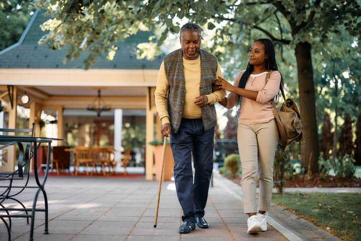 A Granddaughter Walking With Her Grandfather Outside. 