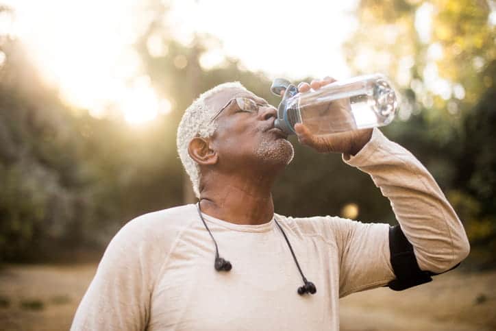 A Senior Male Drinking Water While Outside. 