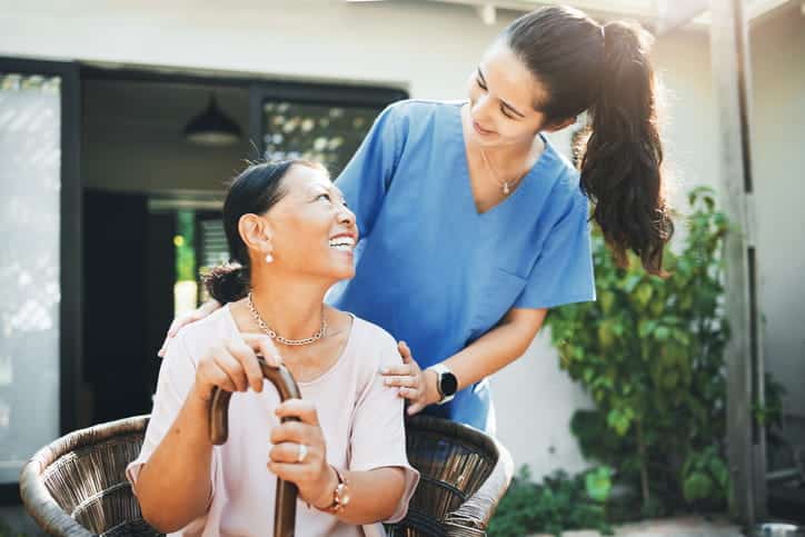 An Aide Smiling With A Patient At A Nursing Home Facility.