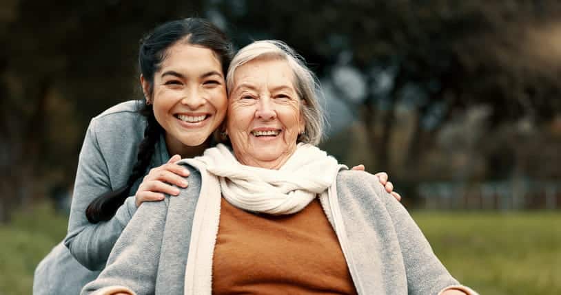 A Health Care Aid Smiling With An Elderly Woman.