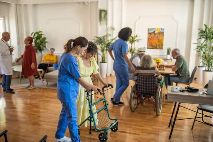 Health Aides Assisting Individuals In A Nursing Home.