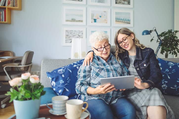 A Woman With Her Grandmother As They Review Photos Together.
