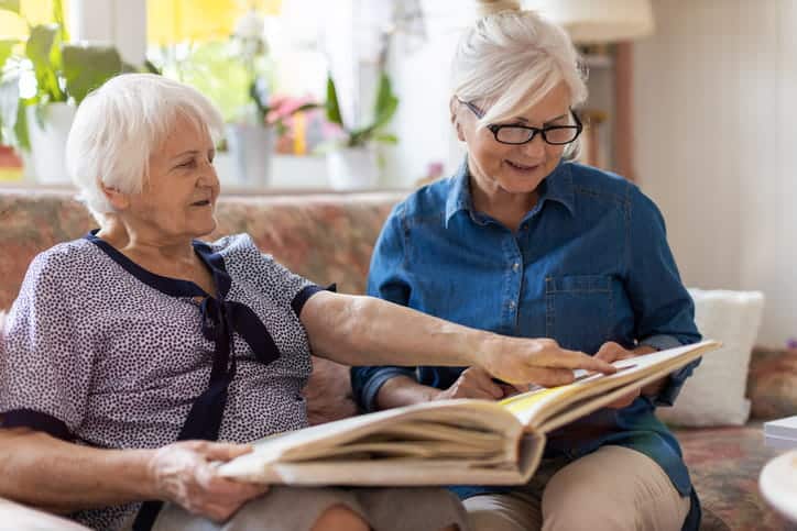 A Woman Reviewing A Picture Book With Her Elderly Mother.