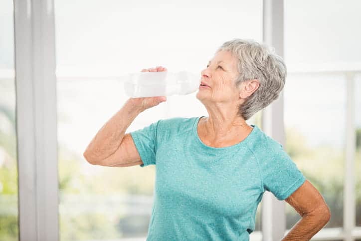 A Senior Woman Drinking Water To Rehydrate.