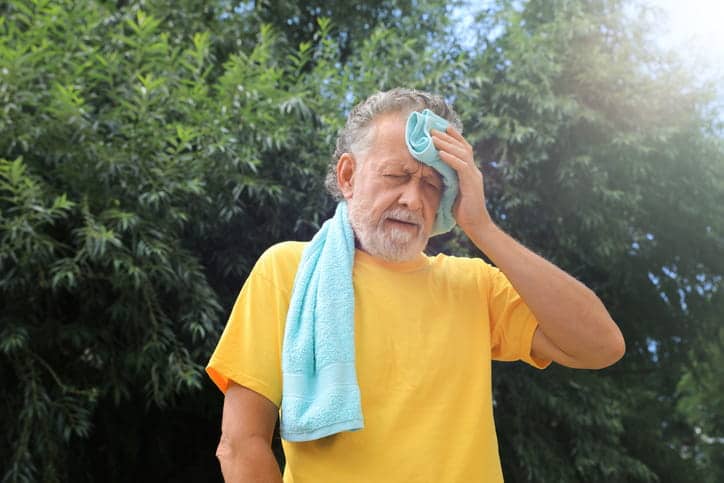 An Elderly Male Wiping Sweat Off His Forehead With A Towel During The Summer.
