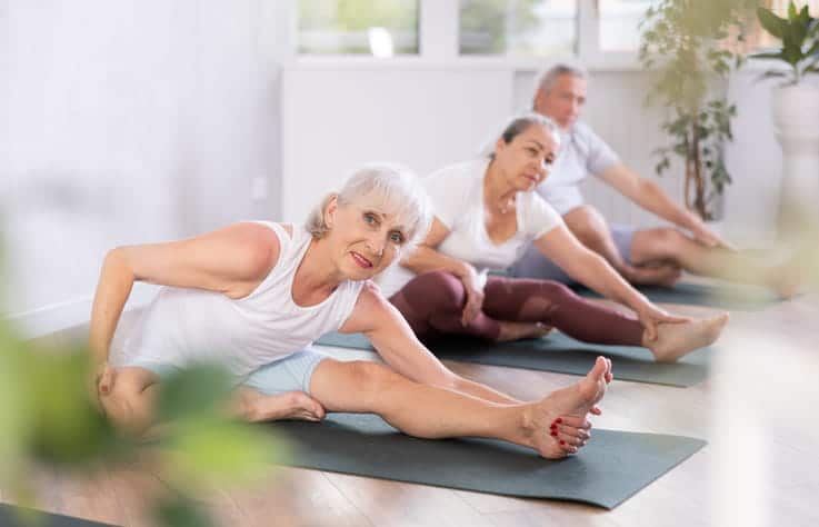 A Group Of Three Seniors Doing Yoga Together To Stay Active.