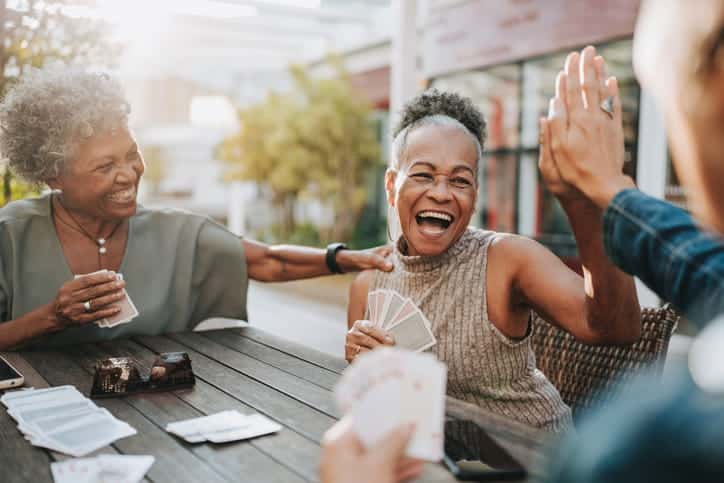 Senior Women Laughing Together As They Play A Card Game.