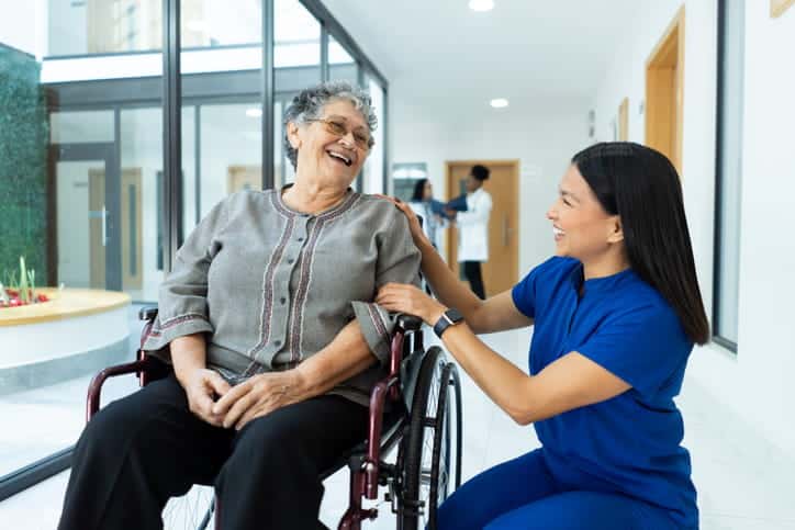 A Nurse Assisting A Patient In A Wheelchair At A Skilled Nursing Facility.