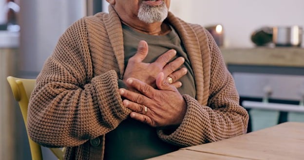 A Senior Holds His Chest And Wrist In Pain.
