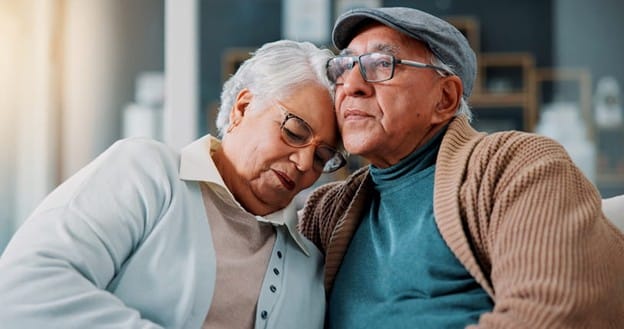 A Man Visits His Wife In A Memory Care Facility And Gives Her A Hug.