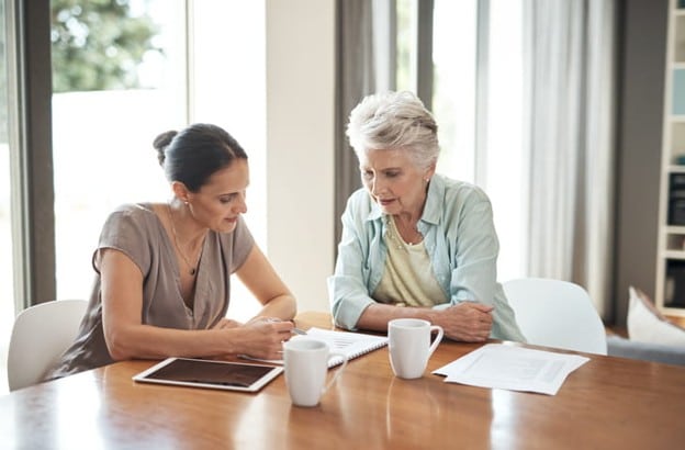 A Woman With Her Elderly Mother Go Over A Care Plan.