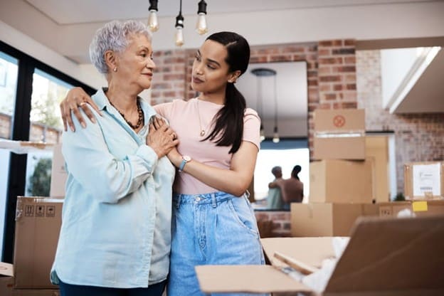 A Daughter Hugs Her Elderly Mother As They Pack Up Her Belongings.