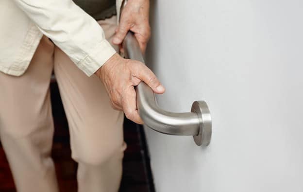 An Wlderly Woman Who Is Holding A Handrail For Support.